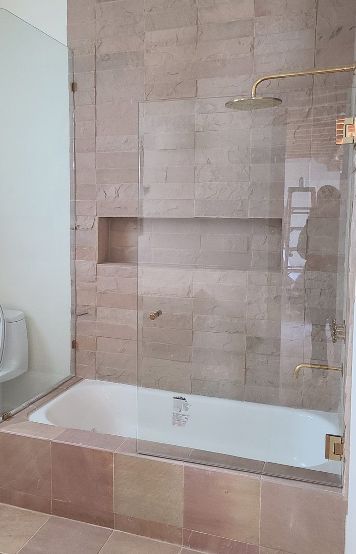 Travertine tub and shower with brass rainhead