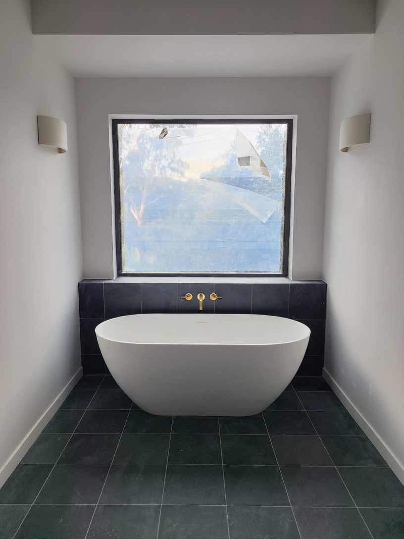 Freestanding tub framed by picture window