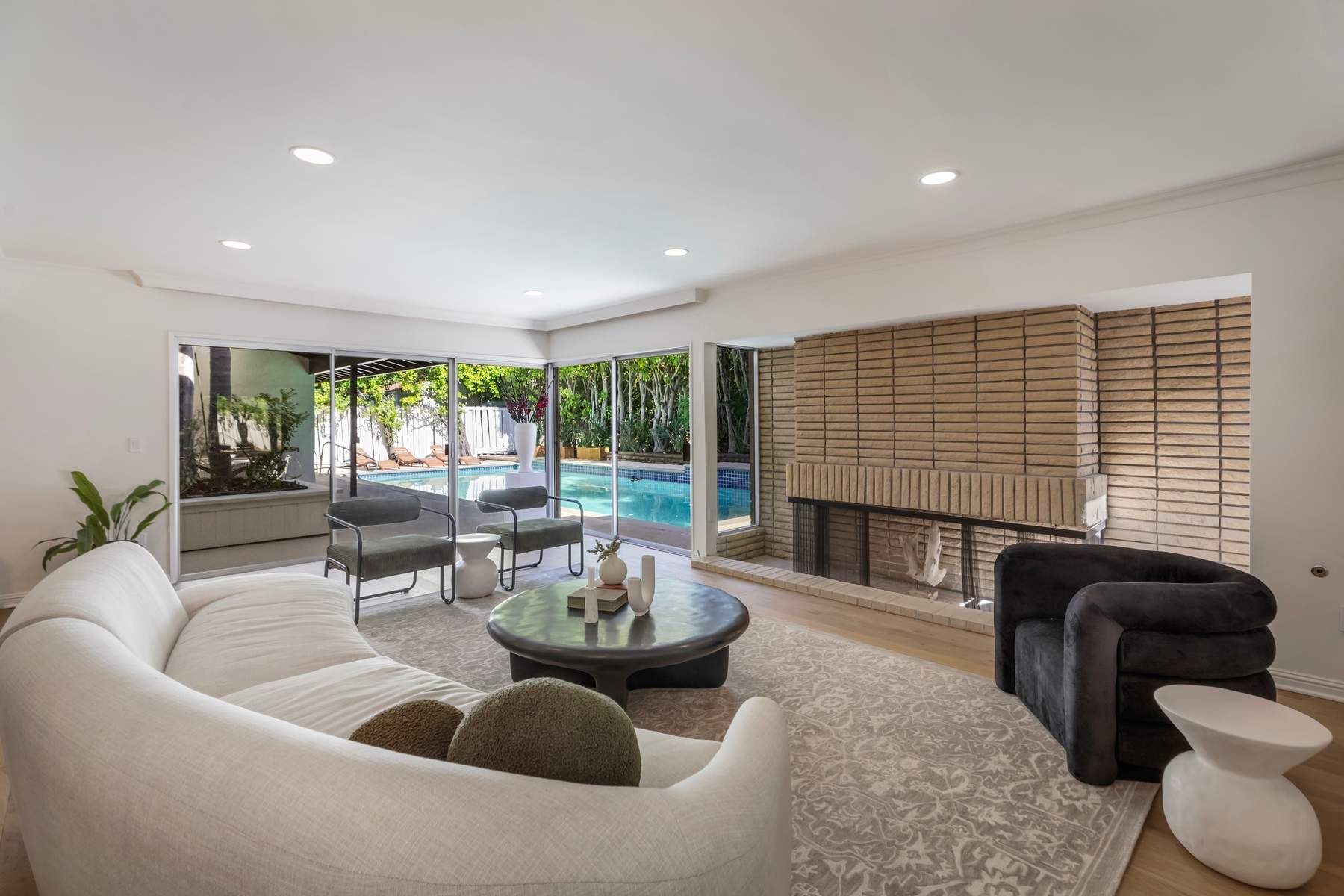 Living room with brick fireplace opening to the pool, Nanberry Residence Encino