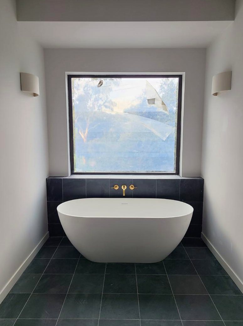 Freestanding tub framed by picture window, The Linear House